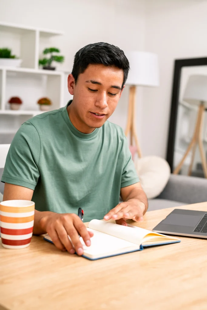 Joven revisando apuntes y estudiando desde casa, asociado a la educación financiera, aprendizaje continuo y organización para emprendedores.