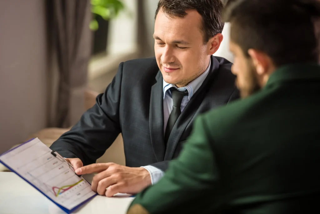 Asesor financiero revisando con un cliente las condiciones de un crédito vía nómina, analizando costos, plazos y documentación en un proceso formal, transparente y seguro para trabajadores del GEM.