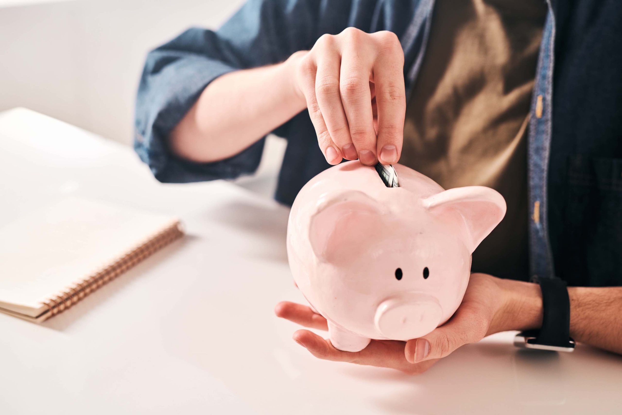 Hombre ahorrando dinero. Colocando dinero en alcancía con forma de cerdo. Formas de ahorrar dinero