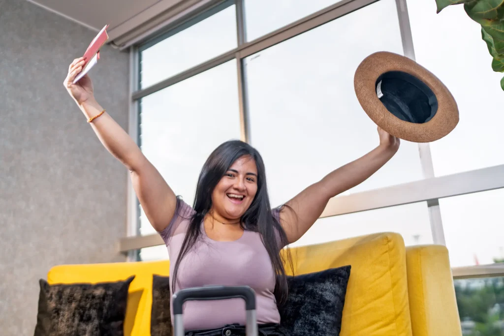 Mujer celebrando en el aeropuerto antes de viajar, ilustrando cómo un préstamo personal de Lanamóvil puede ayudar a financiar unas vacaciones sin complicaciones.