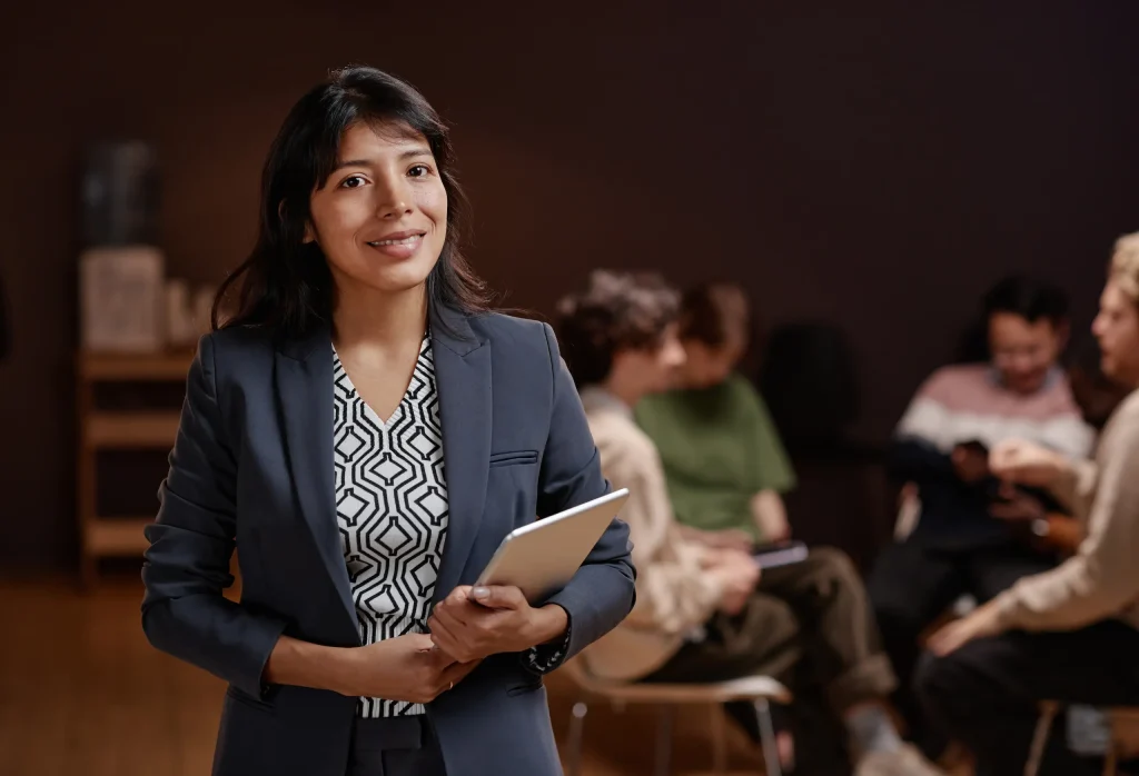 Mujer con traje formal y estudiantes atrás.