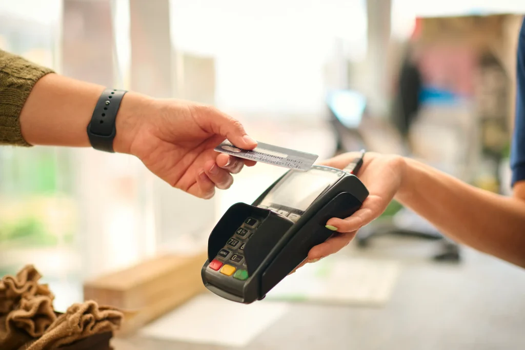 Persona realizando un pago con tarjeta de crédito, representando el uso responsable de productos financieros y el cuidado del historial crediticio. 