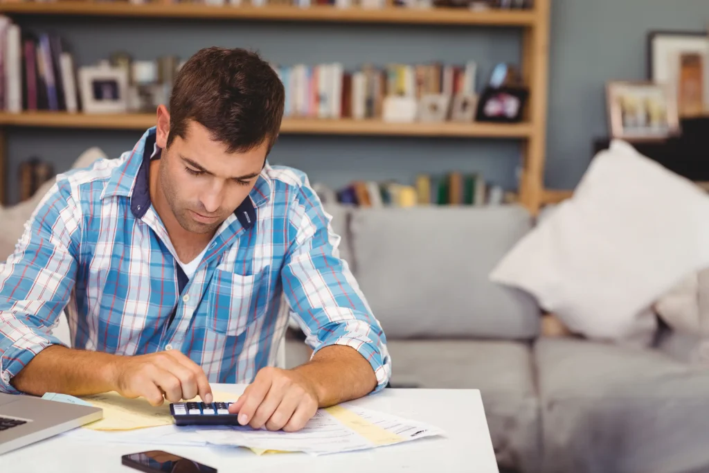 Hombre revisando cuentas y calculando gastos del hogar antes de solicitar un financiamiento, representando la importancia de organizar pagos y mantener estabilidad financiera durante una remodelación.
