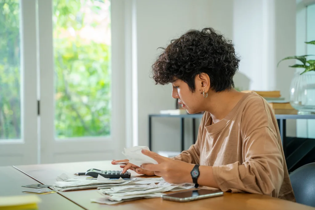 Mujer revisando cuentas y gastos del hogar antes de solicitar un financiamiento para remodelación, representando la importancia de evaluar pagos y presupuesto.