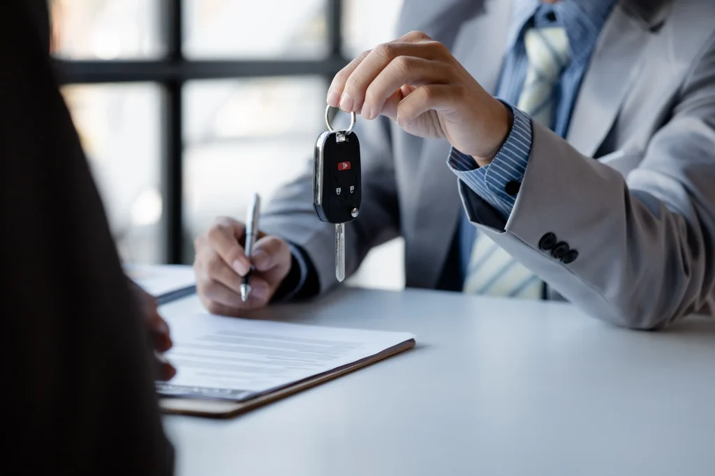 Asesor entrega las llaves de un vehículo a un cliente durante el proceso de compra. La imagen representa una situación en la que un préstamo para enganche de auto puede ayudar a aprovechar una oportunidad y avanzar con la adquisición del coche.