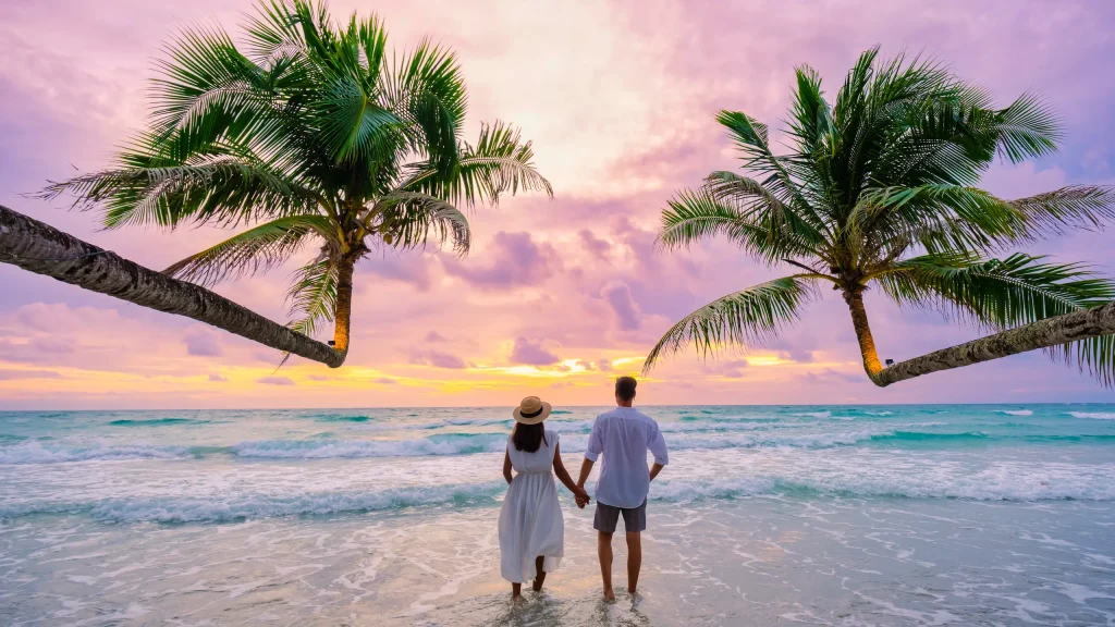Pareja caminando por la playa durante su luna de miel